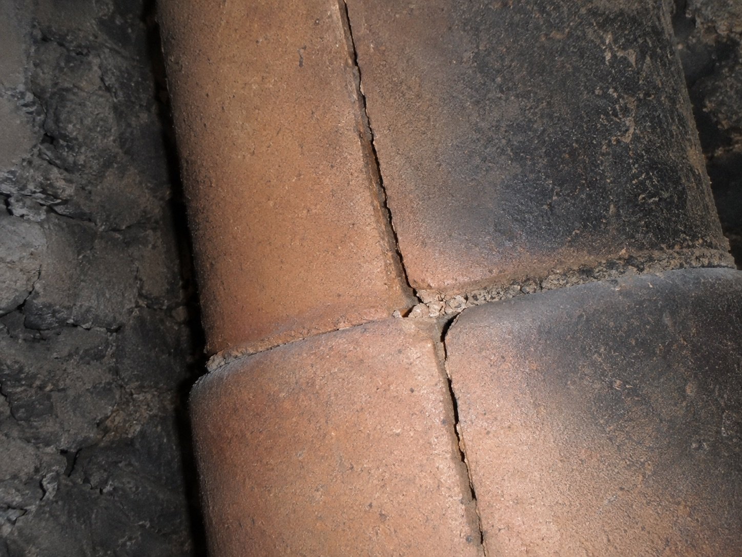 Cracked clay flue tile with a split through the mortar joint