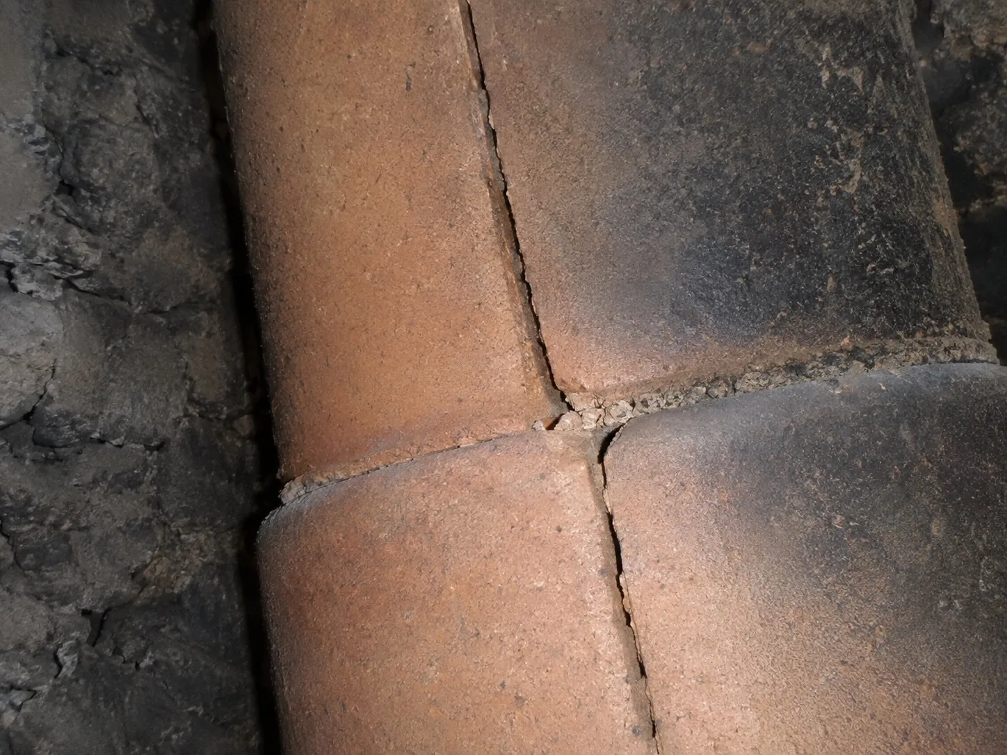 Cracked clay flue tile with a split through the mortar joint