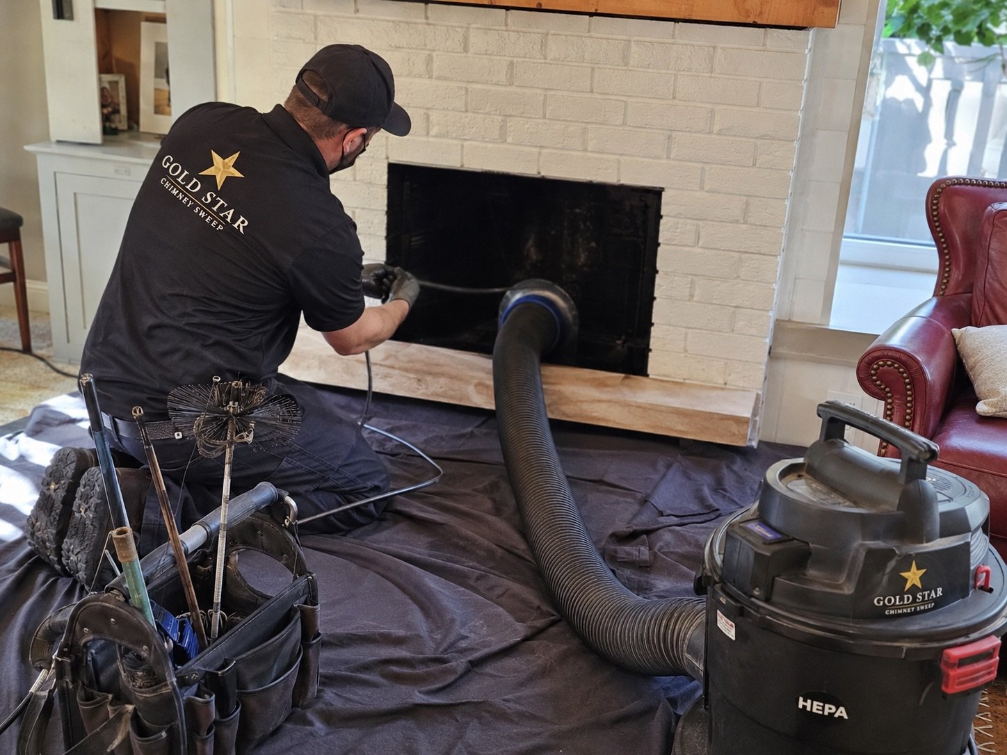 Technician cleaning a fireplace with drop cloths and a vacuum in place